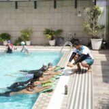Kids swimming – Instructor teaching children swimming with kickboards in pool